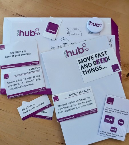 The image shows a collection of promotional materials from GDPRhub and noyb.eu, including stickers, a button, and a postcard. Some of the visible stickers have messages such as 